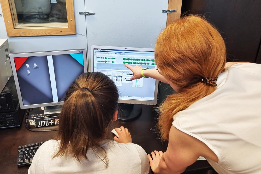 Zwei Personen vor einem Bildschirm bei der Podcast-Produktion.