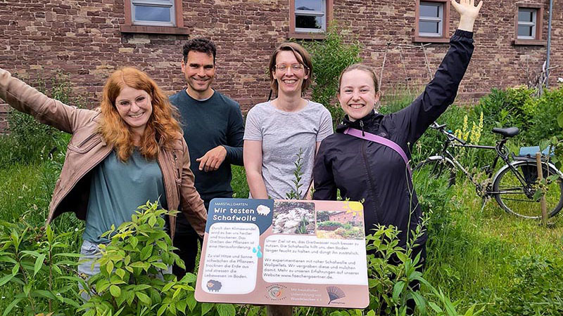 Vier Personen freuen sich über ein Infoschild im Marstallgarten.