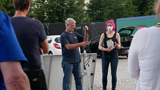Gruppe von Menschen bei einem Workshop zu PV-Solarmodulen im Außenbereich.