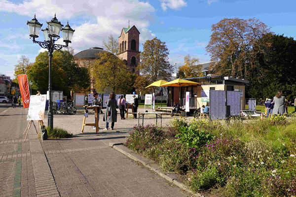 Blick auf einen belebten Friedrichsplatz mit dem MobiLab im Hintergund.