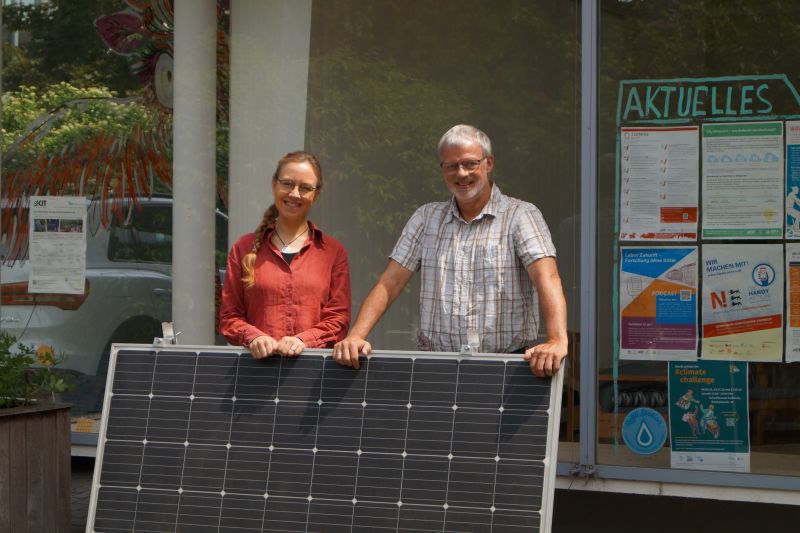 Die Forschenden desProjekts NEEDS stehen mit einem Solarmodul vor dem Zukunftsraum