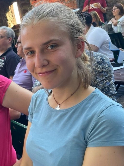 Nahaufnahme einer lächelnden Person im blauen Oberteil.
