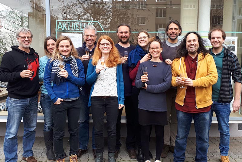Teamfoto vom Quartier Zukunft-Team vor dem Zukunftsraum, sie halten Sektgläser in der Hand.